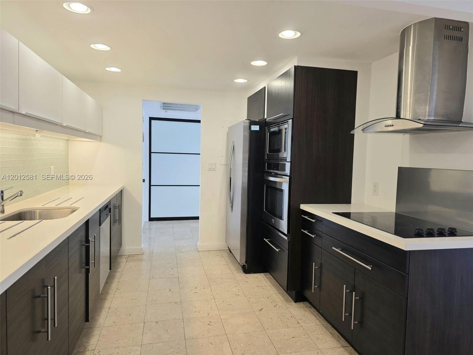 A modern kitchen features dark wood cabinetry, stainless steel appliances, and white countertops — 1800 NE 114th St # 706, Miami FL 33181, MIAMI, FL