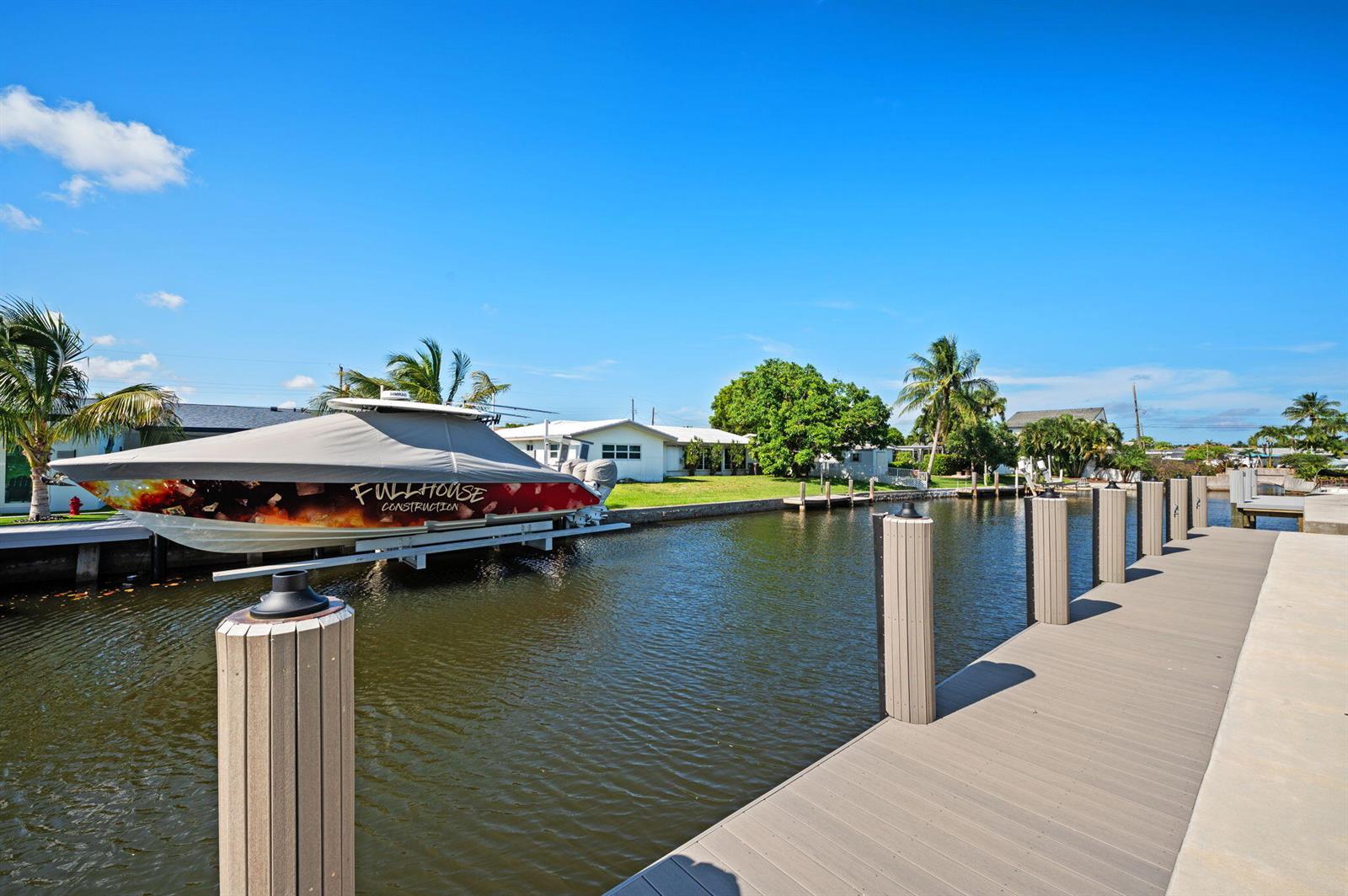 A modern white house under construction sits next to a wooden dock and canal — 1410 Florian Drive, Dania Beach FL 33004, DANIA BEACH, FL