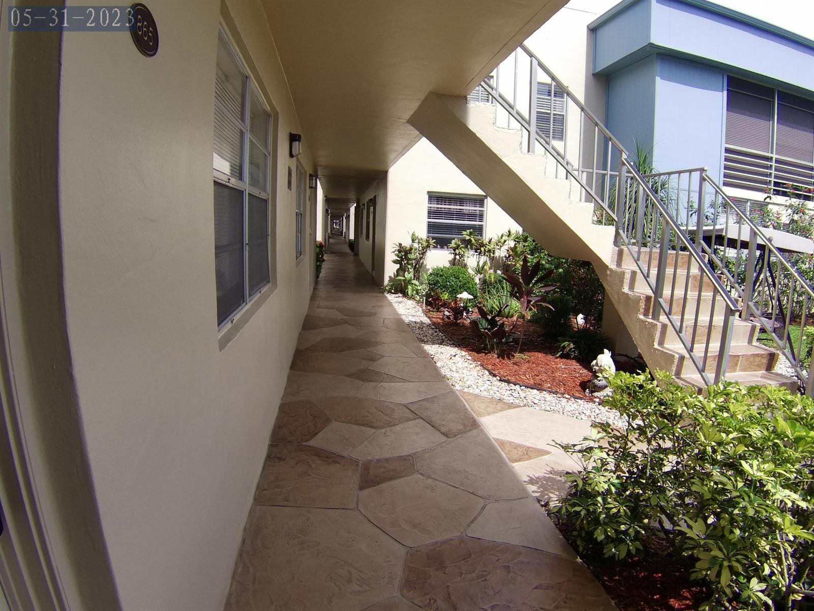 An outdoor walkway leads past a garden area and a staircase at an apartment complex — 865 Flanders S, Delray Beach FL 33484, DELRAY BEACH, FL