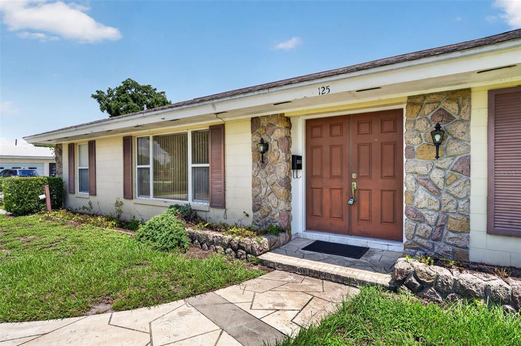 A single-story house exterior features a stone facade, double front doors, and a walkway — 125 E FAITH TERRACE, MAITLAND, FL
