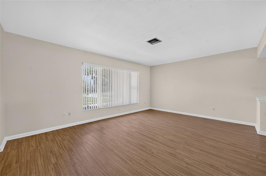 An empty room features light-colored walls, wood-look flooring, and a large window with vertical blinds — 125 E FAITH TERRACE, MAITLAND, FL