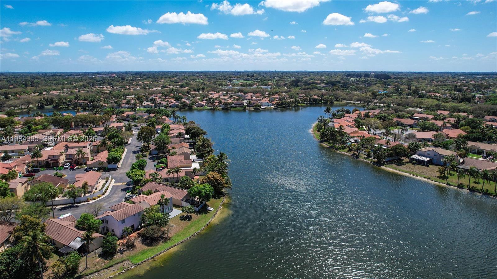 An aerial view shows a residential neighborhood with houses surrounding a large lake — 1354 NW 126th Way, Sunrise FL 33323, SUNRISE, FL