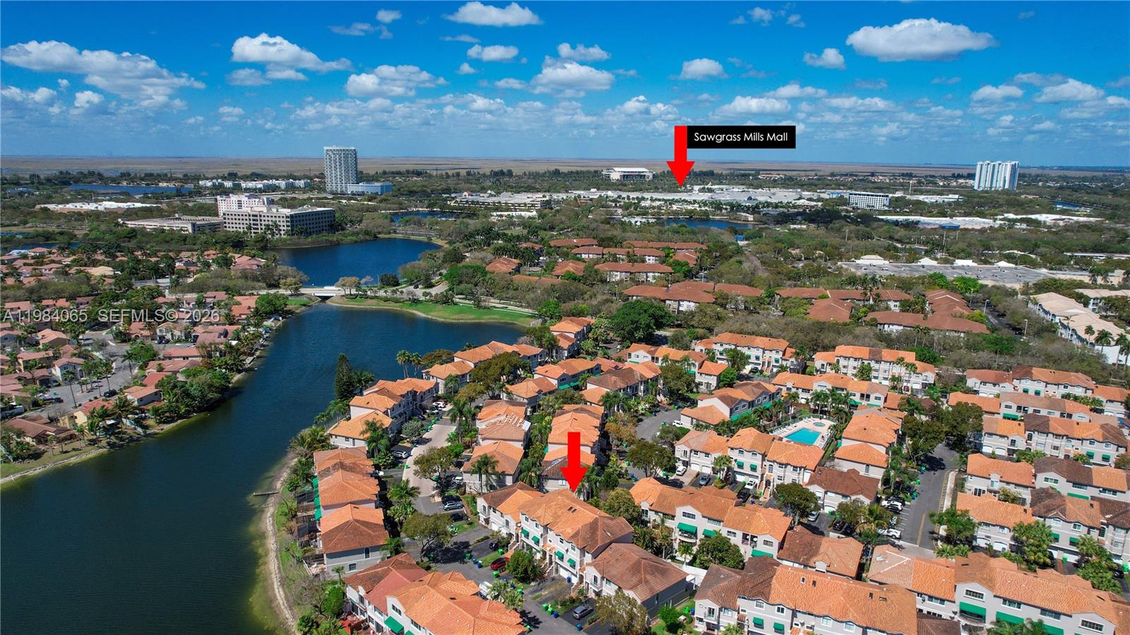 An aerial view shows a residential townhouse community with a lake and distant shopping mall — 1354 NW 126th Way, Sunrise FL 33323, SUNRISE, FL