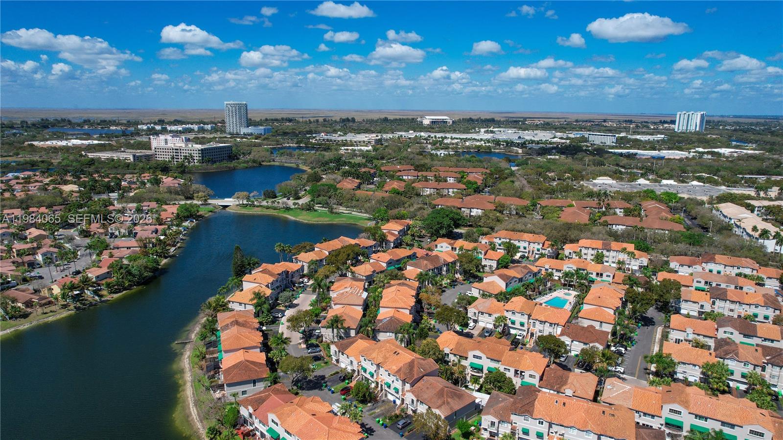 An aerial view shows a residential community with townhomes, a lake, and surrounding greenery — 1354 NW 126th Way, Sunrise FL 33323, SUNRISE, FL