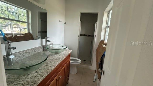A bathroom features a granite vanity with two glass vessel sinks and a walk-in shower — 2506 SANDY LANE, ORLANDO, FL