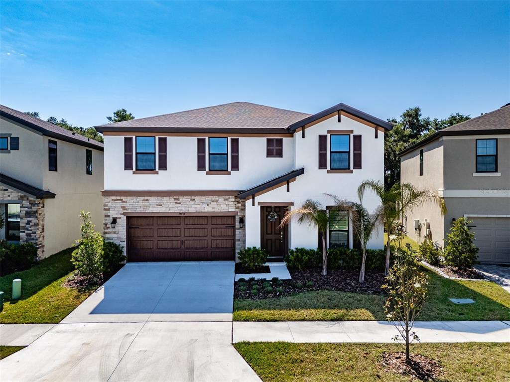 A two-story suburban house with a white stucco exterior, stone accents, and a garage — 14733 GALLOP RUN DRIVE, LITHIA, FL