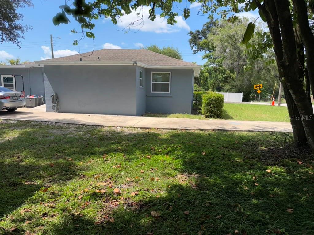 A single-story gray house with a bright orange front door and a white metal railing — 703 E HAMILTON AVENUE, TAMPA, FL