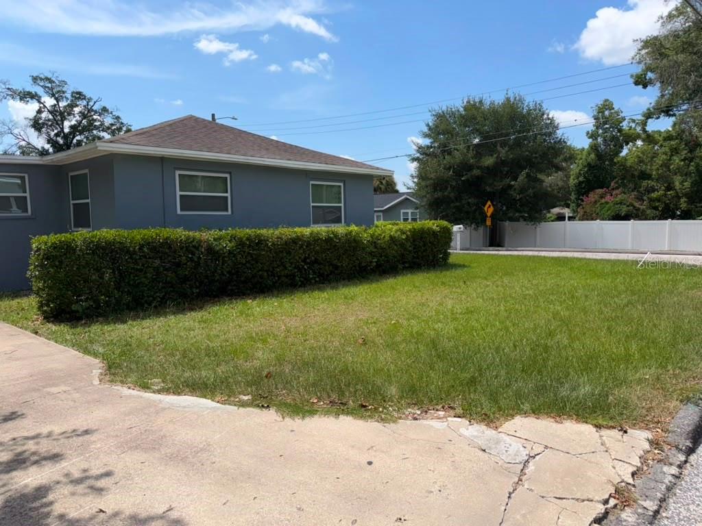 A gray, single-story house with a hedge in the front yard under a blue sky — 703 E HAMILTON AVENUE, TAMPA, FL