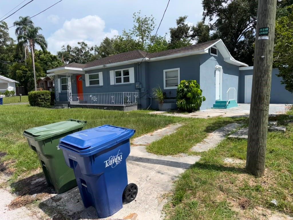 A blue house exterior features a concrete driveway, a small porch, and a white door — 703 E HAMILTON AVENUE, TAMPA, FL