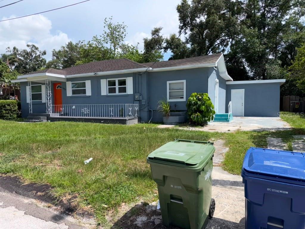 A gray exterior wall of a house with a concrete driveway and a grassy yard — 703 E HAMILTON AVENUE, TAMPA, FL