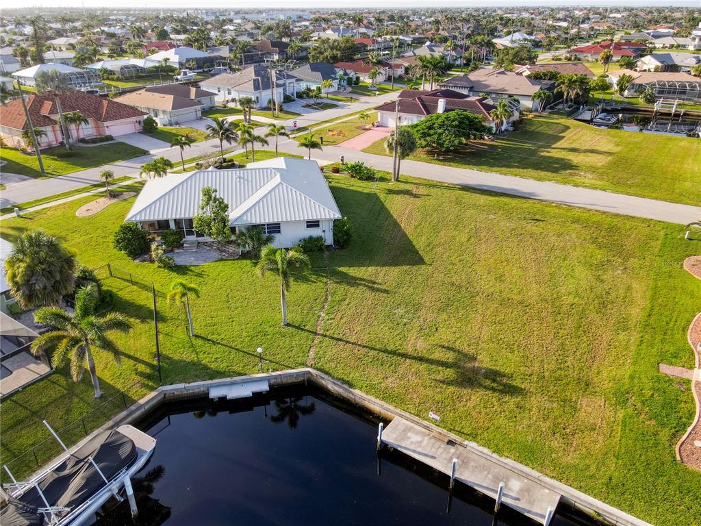 An aerial view shows a white house with a metal roof beside a canal — 2500 RIO LISBO COURT, PUNTA GORDA, FL