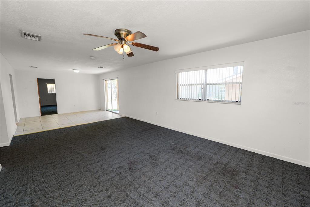 A living room with dark gray carpeting, white walls, a ceiling fan, and tile flooring — 2170 ROHR DRIVE, BARTOW, FL