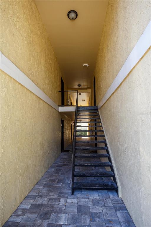 An outdoor stairwell leads to an upper landing between two yellow stucco walls — 908 LAKE DESTINY ROAD UNIT E, ALTAMONTE SPRINGS, FL