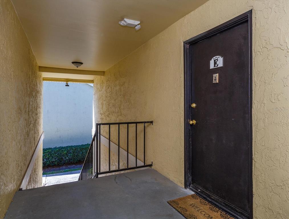 A dark brown door labeled E opens onto a concrete landing with a metal railing — 908 LAKE DESTINY ROAD UNIT E, ALTAMONTE SPRINGS, FL