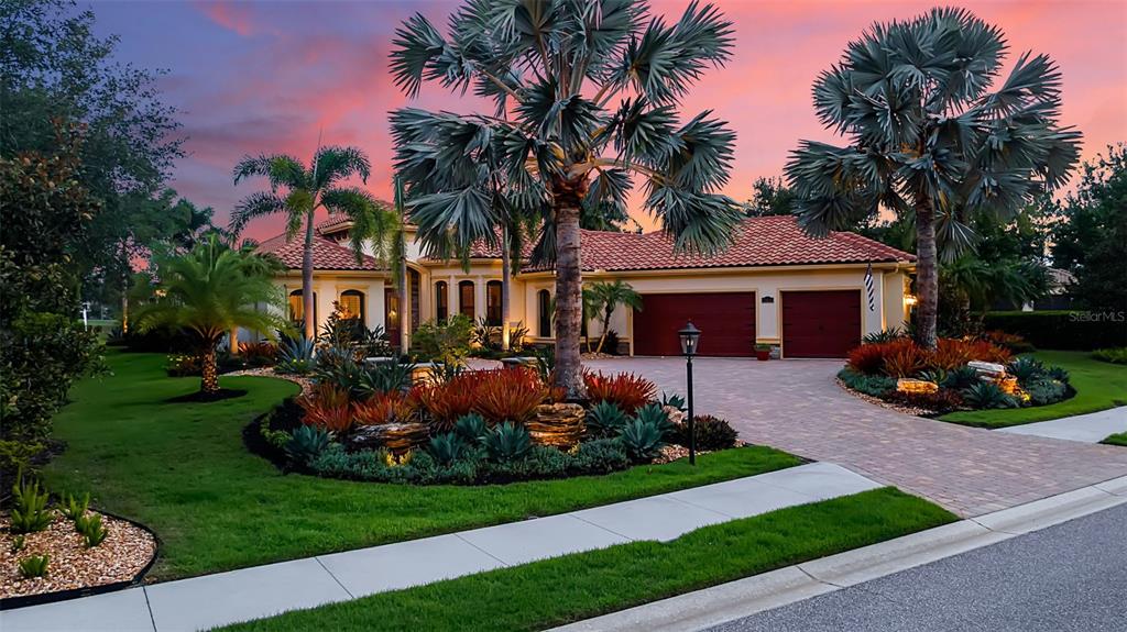 A single-story house with a tile roof, two-car garage, and landscaped front yard at sunset — 15114 LINN PARK TERRACE, LAKEWOOD RANCH, FL