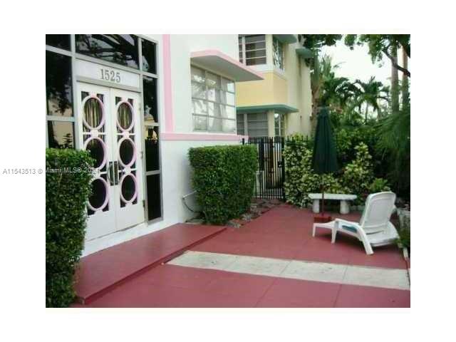 A white building entrance with decorative doors and a patio area featuring a lounge chair — 1525 Meridian Ave # 207, Miami Beach FL 33139, MIAMI BEACH, FL