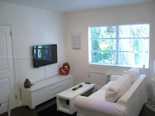 A living room features a white sofa, a television mounted on the wall, and a console — 1525 Meridian Ave # 207, Miami Beach FL 33139, MIAMI BEACH, FL