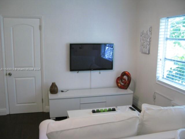 A living room features a wall-mounted television above a white media console and sofa — 1525 Meridian Ave # 207, Miami Beach FL 33139, MIAMI BEACH, FL