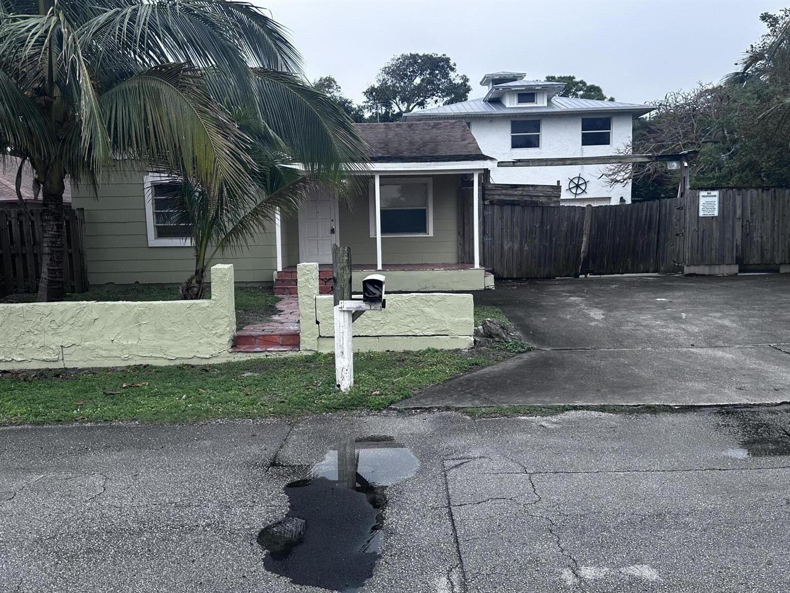 A single-story green house with a front porch, a palm tree, and a paved driveway — 130 NE 4th Avenue, Boynton Beach FL 33435, BOYNTON BEACH, FL