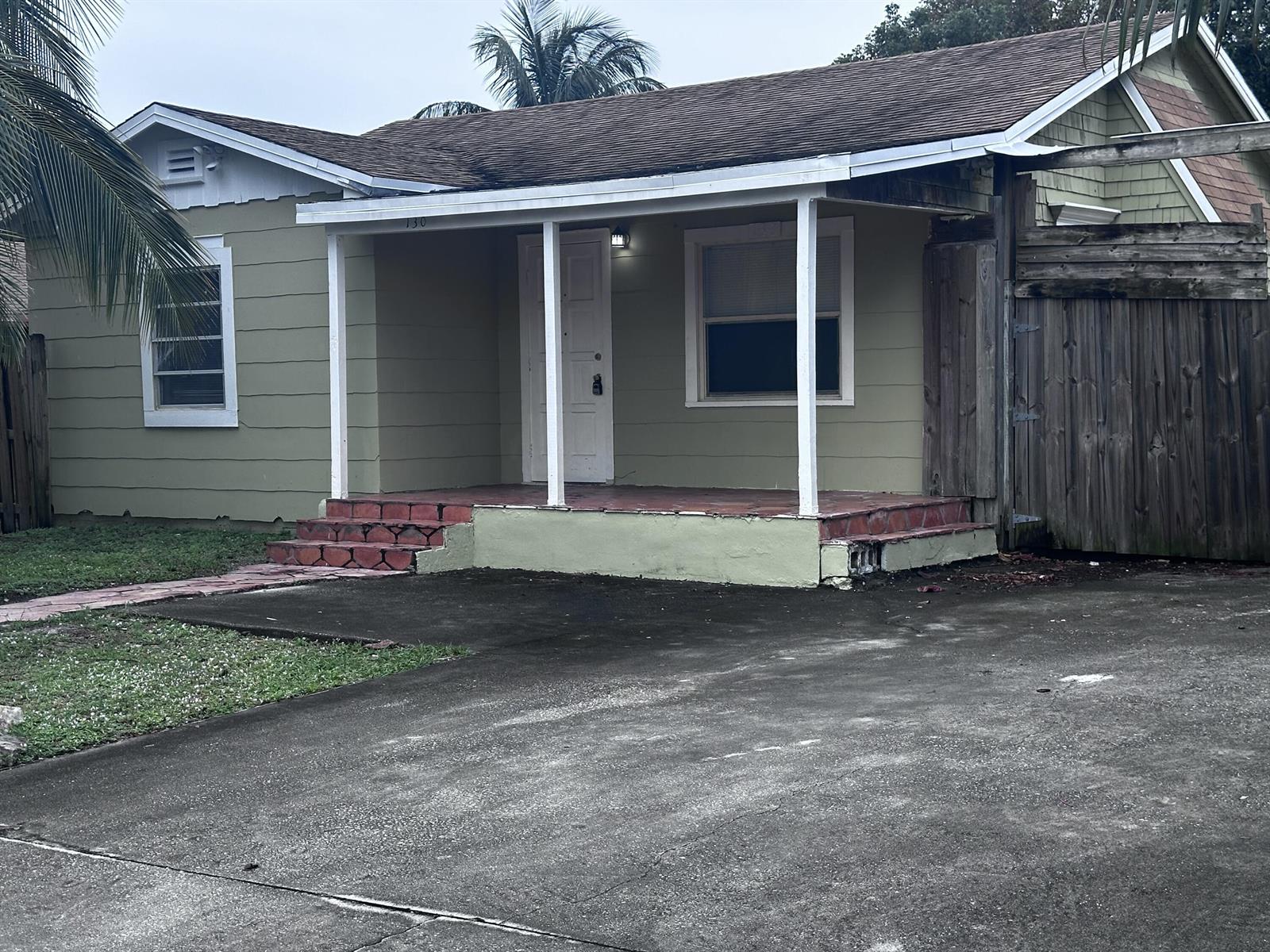 A single-story house with green siding, a covered front porch, and a concrete driveway — 130 NE 4th Avenue, Boynton Beach FL 33435, BOYNTON BEACH, FL