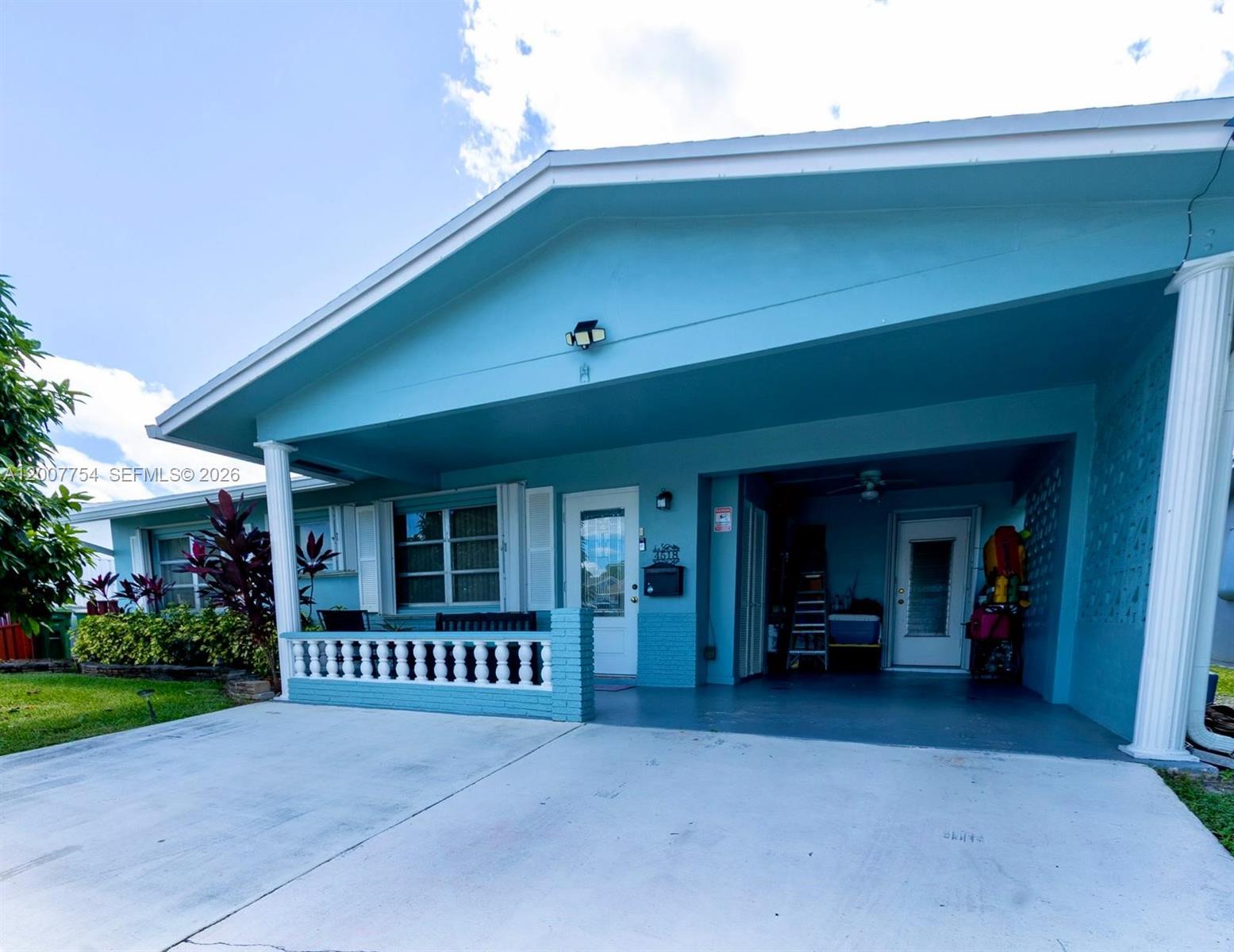 A light blue house features a covered porch, a concrete driveway, and white columns — 4518 NW 45th Ct, Tamarac FL 33319, TAMARAC, FL