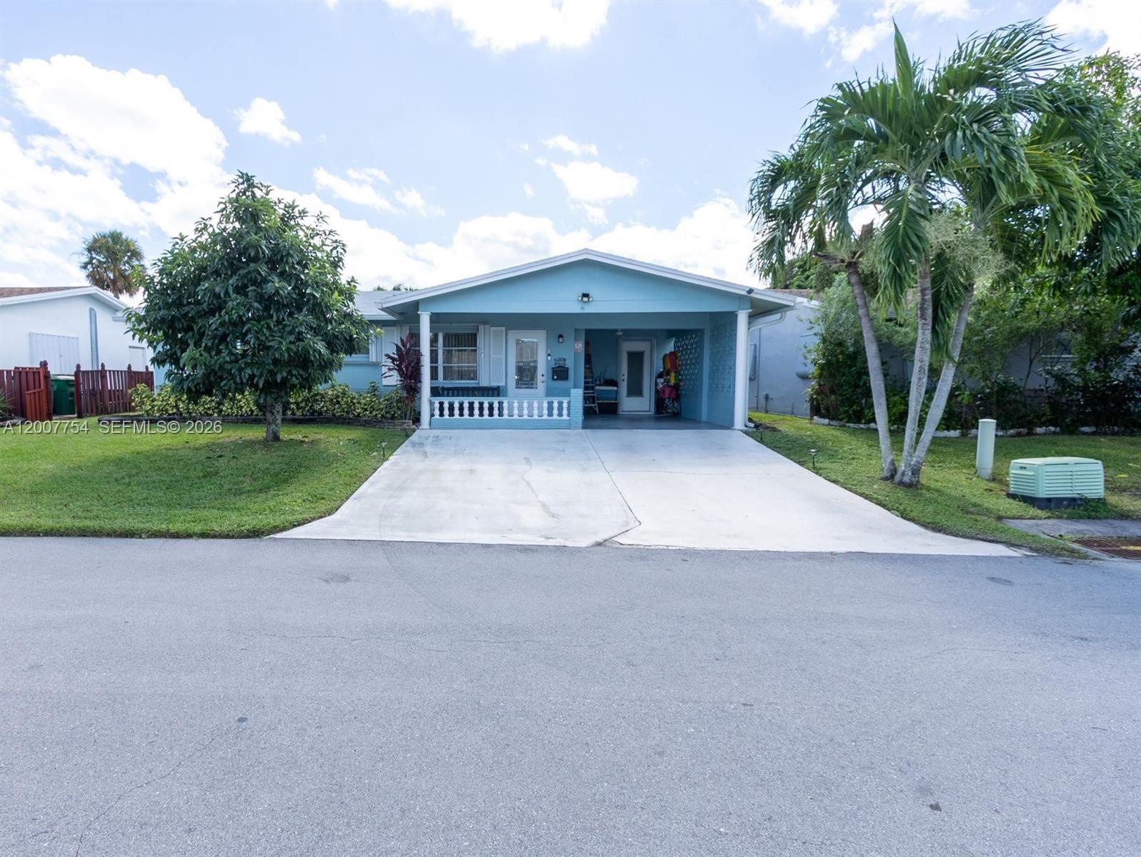 A light blue single-story house features a front porch, a carport, and a concrete driveway — 4518 NW 45th Ct, Tamarac FL 33319, TAMARAC, FL