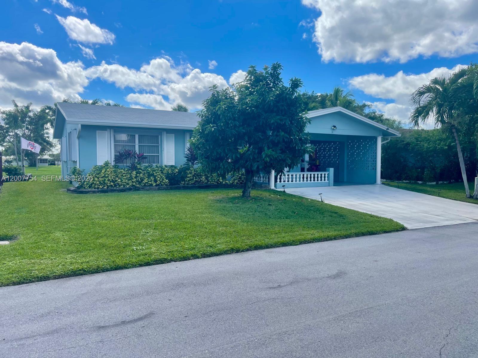 A light blue single-story house features a front lawn, a driveway, and a large tree — 4518 NW 45th Ct, Tamarac FL 33319, TAMARAC, FL