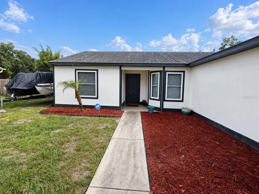 The exterior of a single-story house features white siding, a dark roof, and red mulch — 3055 KIRKLAND STREET, DELTONA, FL