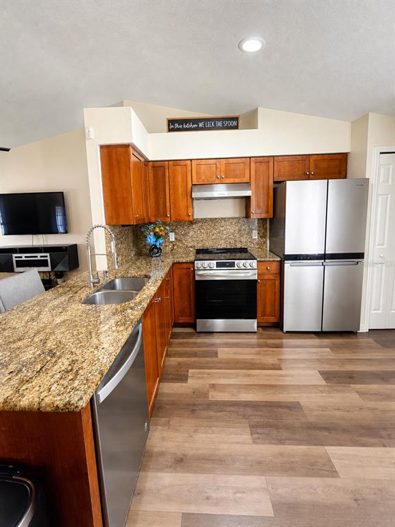 A kitchen features wood cabinets, granite countertops, stainless steel appliances, and wood-look flooring — 3055 KIRKLAND STREET, DELTONA, FL