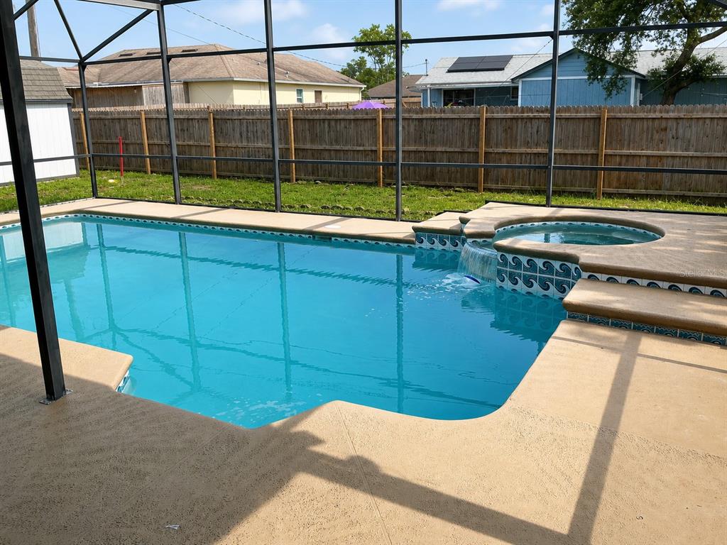 A swimming pool with an attached spa and waterfall feature inside a screened enclosure — 3055 KIRKLAND STREET, DELTONA, FL