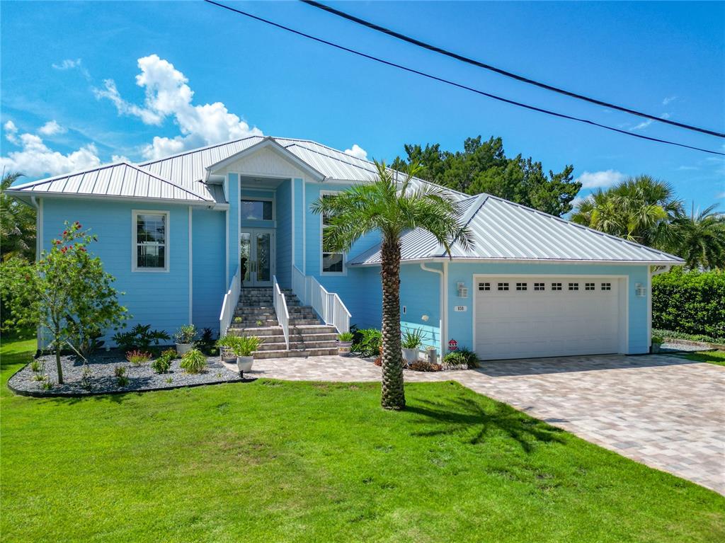 A light blue two-story house features a metal roof, a palm tree, and a garage — 838 SW KINGS BAY DRIVE, CRYSTAL RIVER, FL
