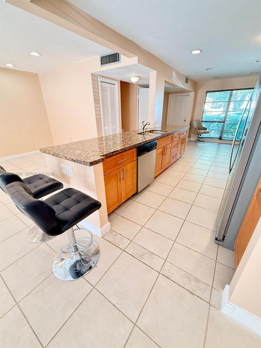 A kitchen features a granite countertop island, wooden cabinets, and tile flooring — 2750 N 34th Ave # 9D, Hollywood FL 33021, HOLLYWOOD, FL