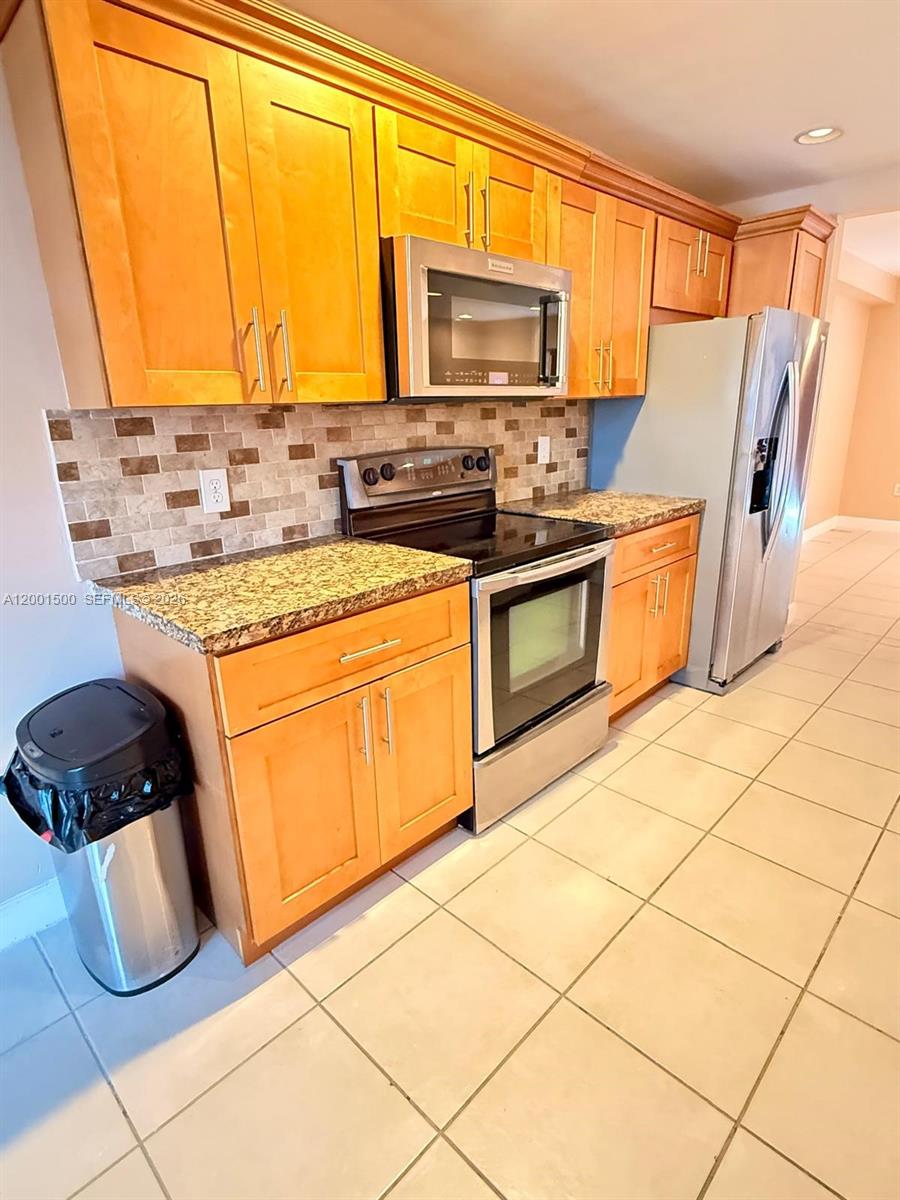 A kitchen features light wood cabinets, granite countertops, stainless steel appliances, and tiled flooring — 2750 N 34th Ave # 9D, Hollywood FL 33021, HOLLYWOOD, FL