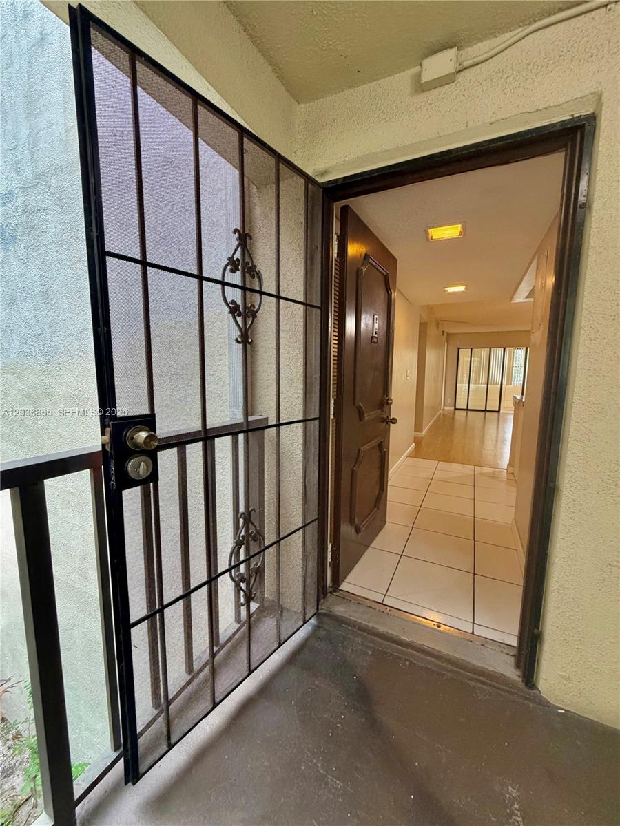 An open security screen door reveals a tiled entryway leading into a sunlit apartment interior — 2320 S Cypress Bend Dr # 206, Pompano Beach FL 33069, POMPANO BEACH, FL