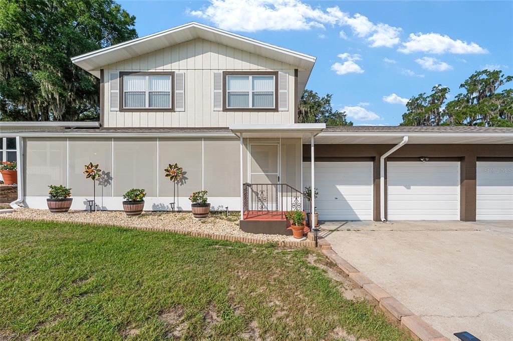 A two-story house features a screened-in porch, a concrete driveway, and an attached garage — 30 EMERALD RUN, OCALA, FL