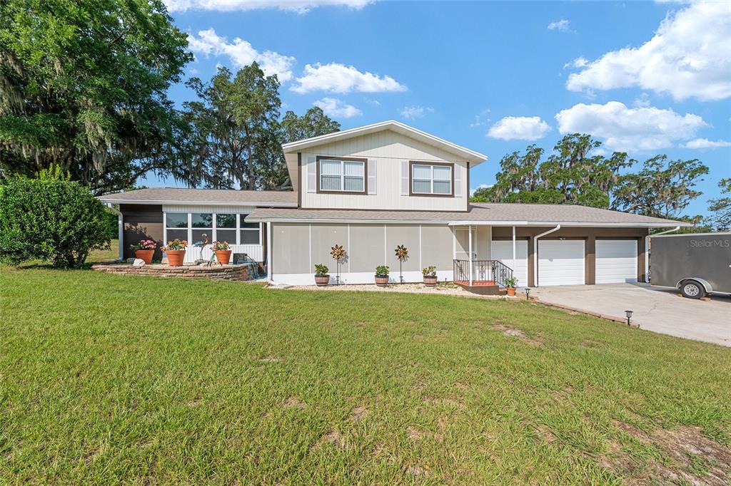A two-story house with a screened-in porch, attached garage, and a large grassy lawn — 30 EMERALD RUN, OCALA, FL