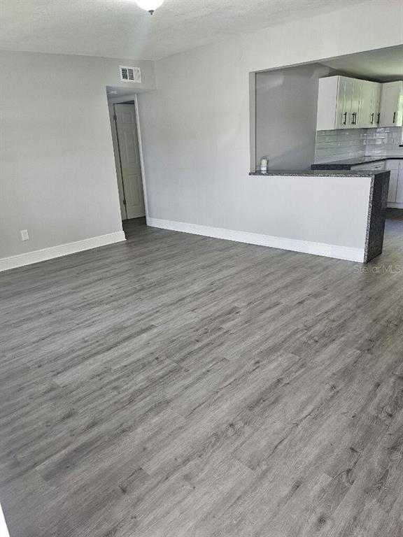 An empty room features light gray walls, white baseboards, and wood-look laminate flooring — 2390 29TH STREET NW, WINTER HAVEN, FL