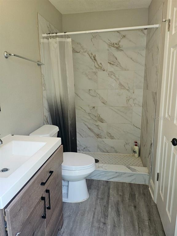 An empty bedroom features gray walls, dark wood-look flooring, and two windows with blinds — 2390 29TH STREET NW, WINTER HAVEN, FL