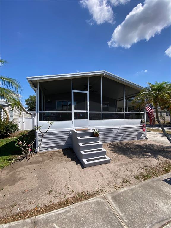 A mobile home exterior features a screened-in porch, gray metal skirting, and concrete steps — 8330 FANTASIA PARK WAY, RIVERVIEW, FL
