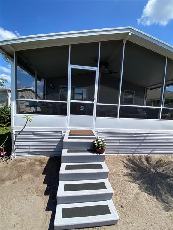 A set of concrete steps with non-slip treads leads to a screened-in porch — 8330 FANTASIA PARK WAY, RIVERVIEW, FL