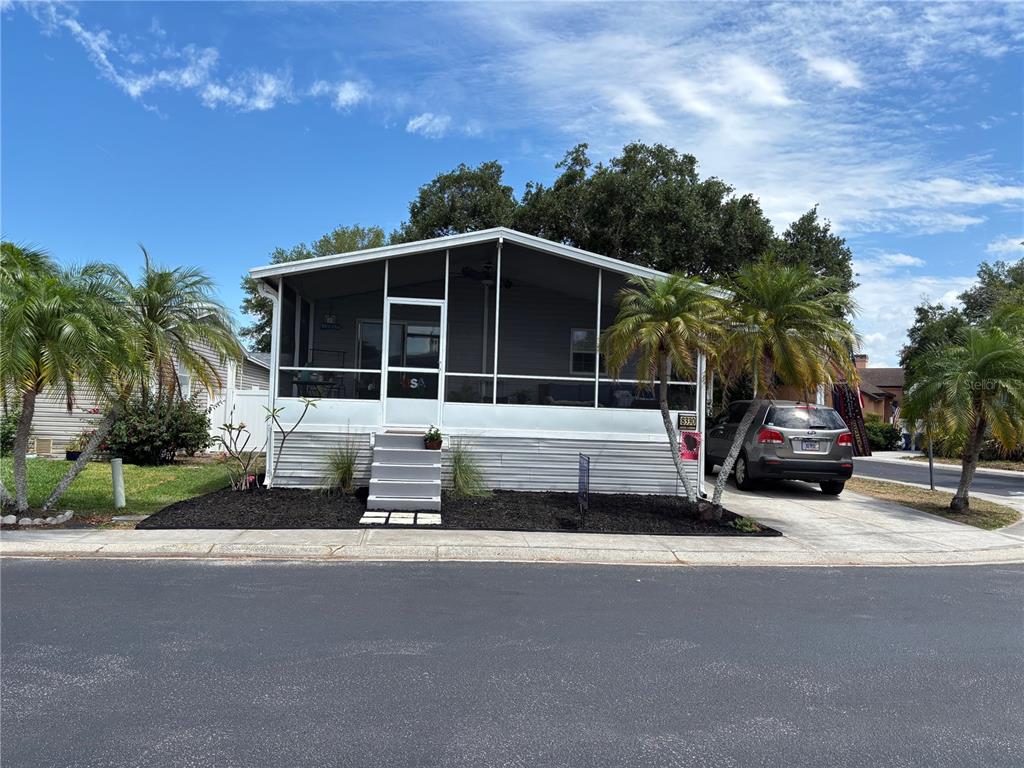 A single-story manufactured home features a screened-in front porch and a concrete driveway — 8330 FANTASIA PARK WAY, RIVERVIEW, FL
