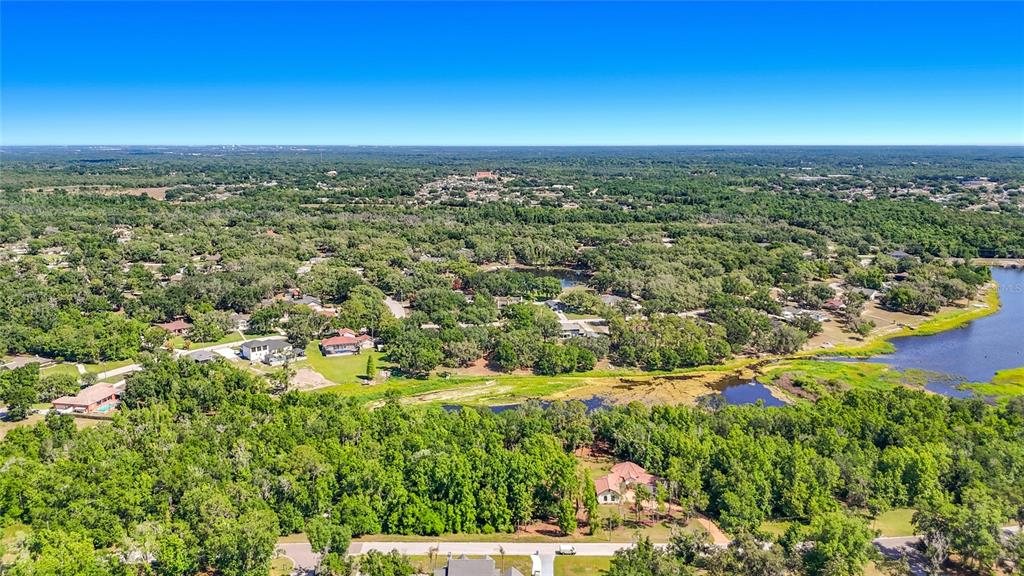 An aerial view shows a residential neighborhood surrounded by dense trees and a small lake — LOT 19  LAKE HILLS DR., RIVERVIEW, FL