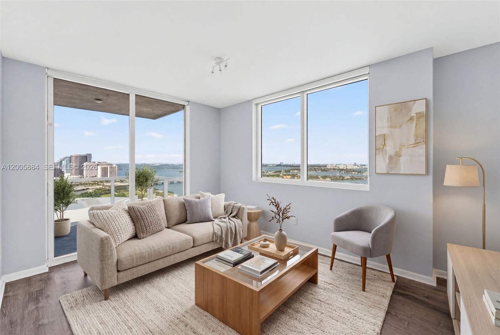 A living room features a beige sofa, wooden coffee table, grey armchair, and floor-to-ceiling windows — 244 Biscayne Blvd # 3702, Miami FL 33132, MIAMI, FL
