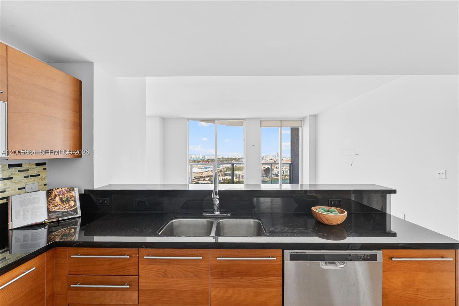 A kitchen features wood cabinets, black countertops, a stainless steel sink, and a city view — 244 Biscayne Blvd # 3702, Miami FL 33132, MIAMI, FL