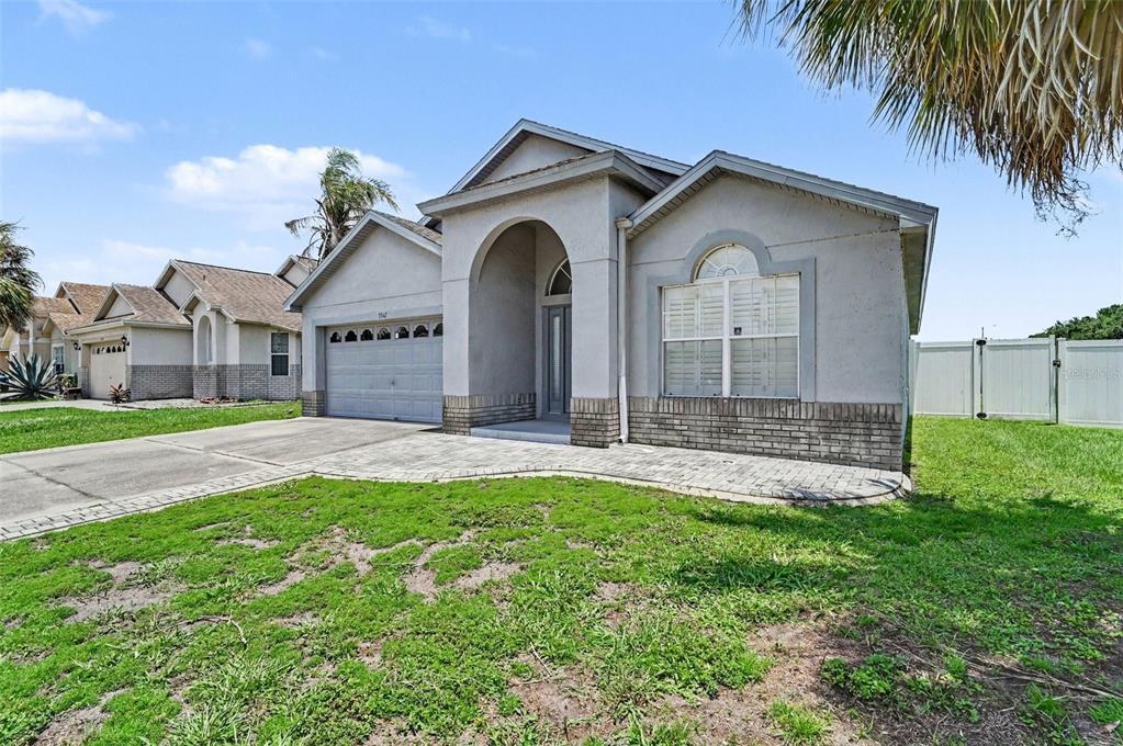 A single-story suburban house with a gray stucco exterior, arched entryway, and a paved driveway — 3342 CRYSTAL CREEK BOULEVARD, ORLANDO, FL
