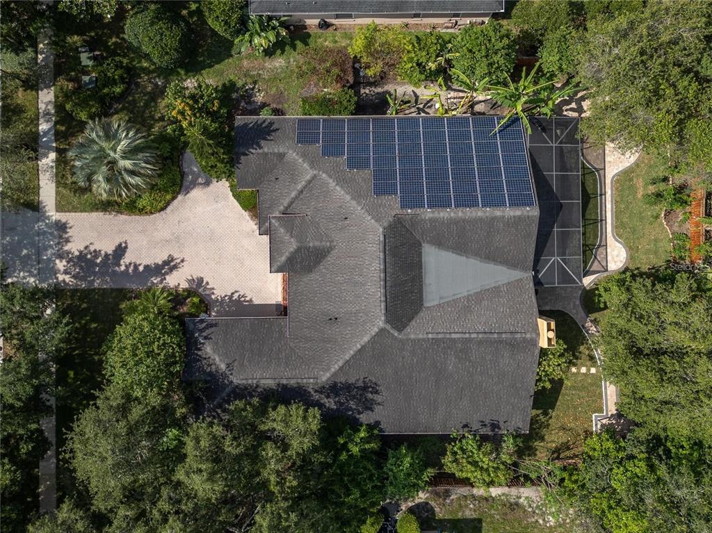 An aerial view shows a house with a large solar panel array on the roof — 140 SEVILLE CHASE DRIVE, WINTER SPRINGS, FL