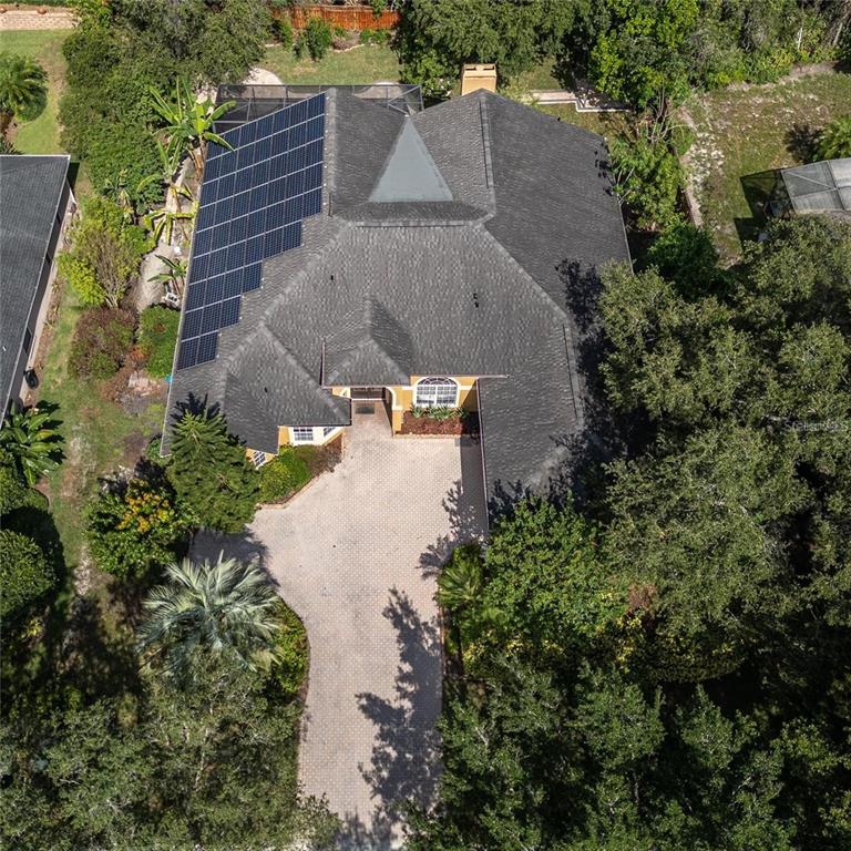 An aerial view of a house with a shingled roof, solar panels, and a paved driveway — 140 SEVILLE CHASE DRIVE, WINTER SPRINGS, FL