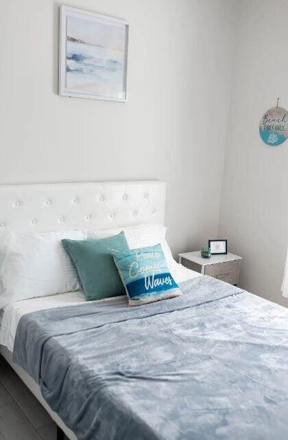 A bedroom features a white tufted headboard, a blue patterned blanket, and beach-themed wall decor — 2682 Nokomis Avenue, FL 33409, FL