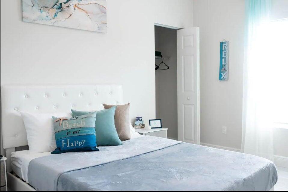 A bedroom features a white tufted headboard, a blue throw blanket, and coastal-themed decor — 2682 Nokomis Avenue, FL 33409, FL