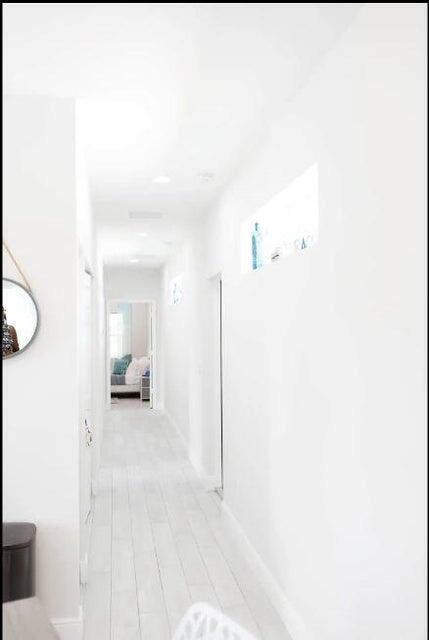 A bright, white hallway features light-colored wood flooring and a small rectangular window — 2682 Nokomis Avenue, FL 33409, FL